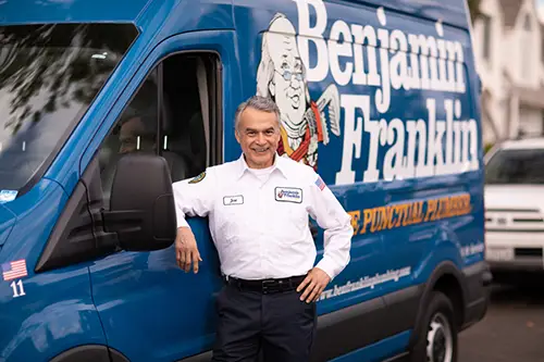 Jose from Benjamin Franklin Plumbing standing in front of his service van