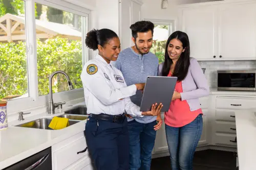 A female Benjamin Franklin Plumbing tech going over a quote with a homeowner couple in their kitchen in Fort Myers