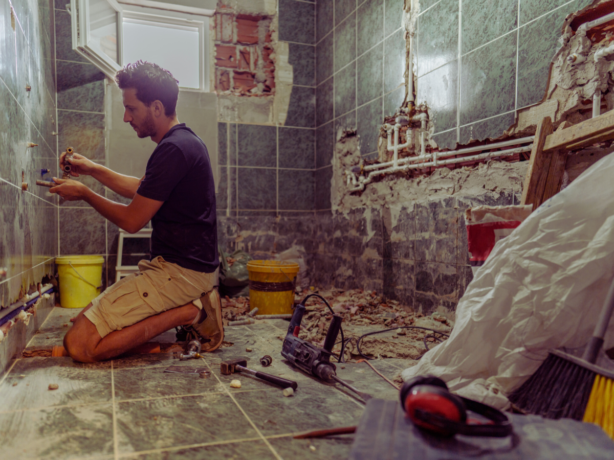 Plumber making sure plumbing fixtures are hooked up to vent stack during bathroom remodel 