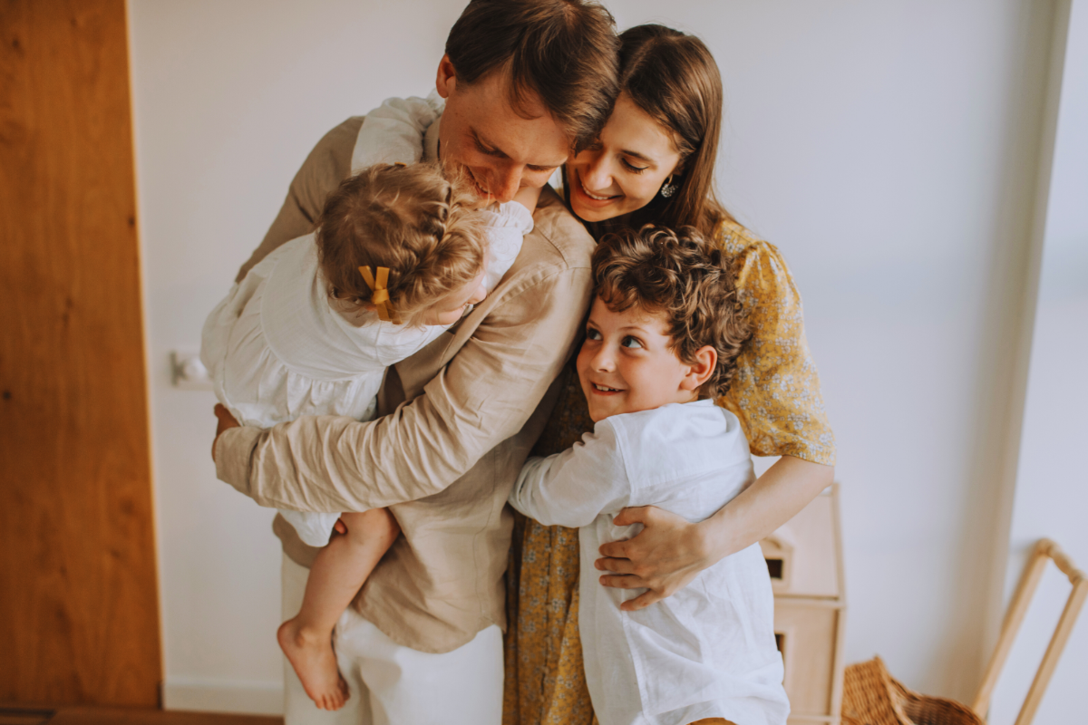 Happy family of four hugging each other